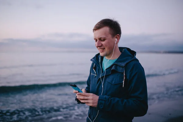 Hombre en auriculares usando el teléfono inteligente . — Foto de Stock