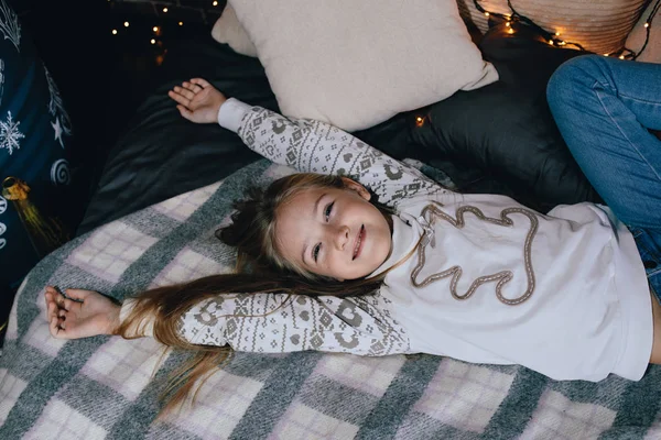 Menina bonita em suéter alongamento na cama . — Fotografia de Stock
