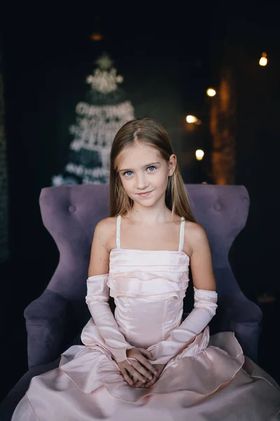 Flicka i elegant klänning sitter i en stol — Stockfoto