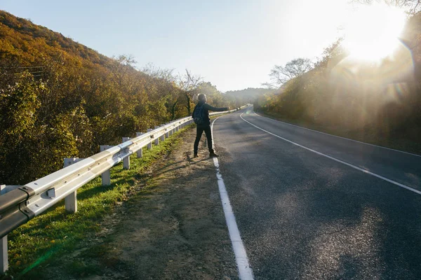 Man hitchhiking on a country road