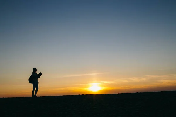 woman taking pictures on camera at sunset
