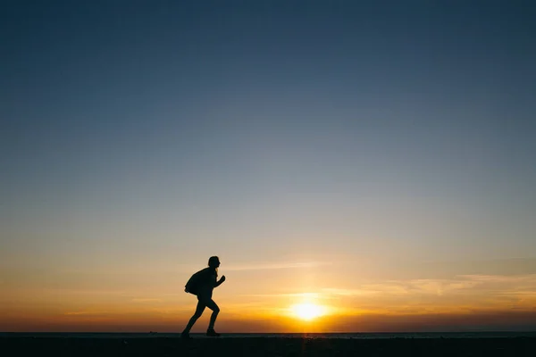 Силуэт бегущей женщины на закате — стоковое фото