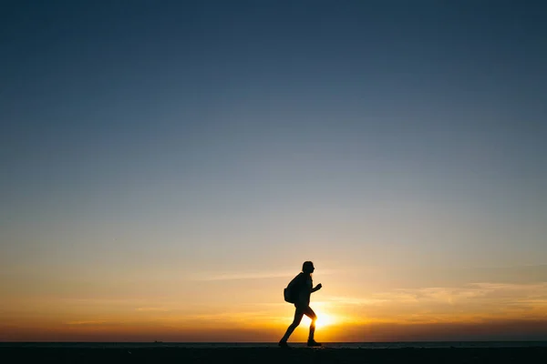 Silhouette of a running woman on sunset — Stock Photo, Image