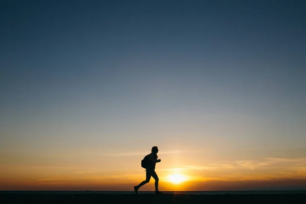 Silhueta de uma mulher correndo no pôr do sol — Fotografia de Stock