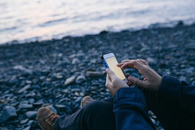 Sahilde cep telefonu kullanan adam