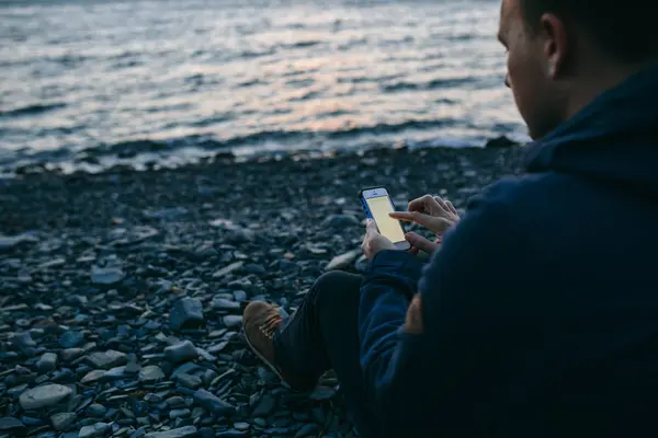 Hombre usando el teléfono celular en la playa — Foto de Stock