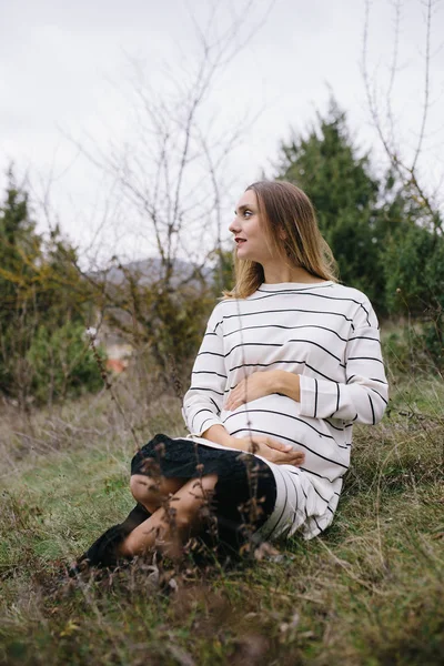 Kobieta w ciąży jest siedząc na trawie — Zdjęcie stockowe