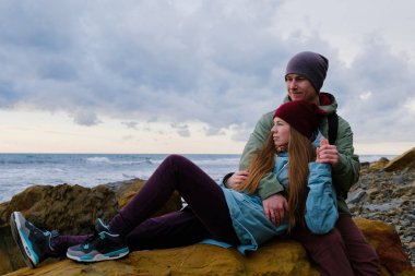 Denizde kayalar üzerine oturan genç Çift
