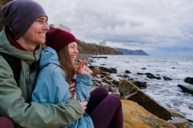 Denizde kayalar üzerine oturan genç Çift