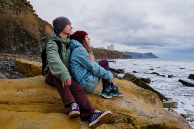 Denizde kayalar üzerine oturan genç Çift