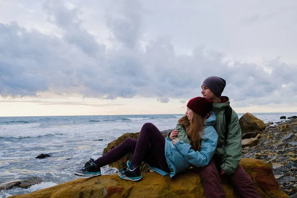 Młoda para siedzi na skałach na morzu — Zdjęcie stockowe