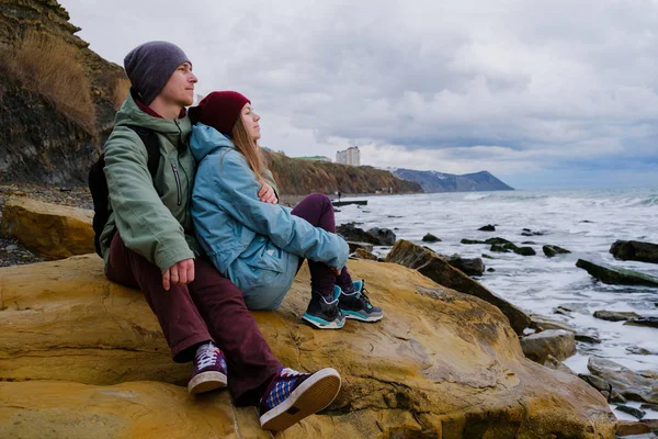 Jeune couple assis sur des rochers en mer — Photo