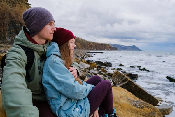 Jeune couple assis au bord de la mer — Photo