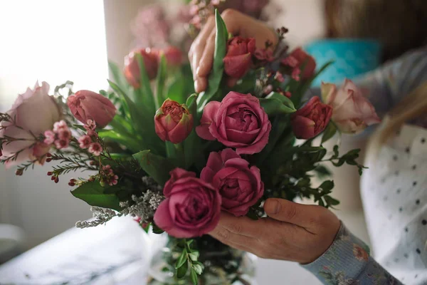 florist making bouquet with roses and tulips