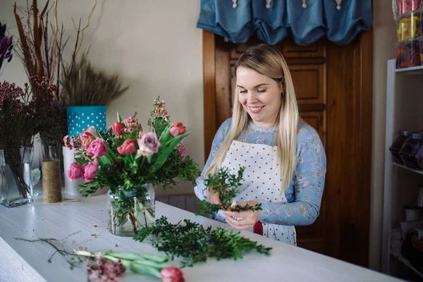 Florist göra bukett med rosor och tulpaner — Stockfoto