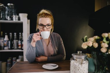 Kafede kahve içen genç bir kadın.