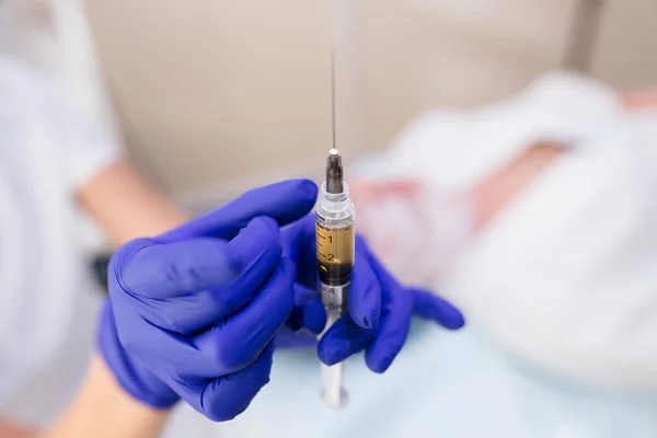 Syringe for medical injection in hands with blue gloves. Nurse or doctor. Liquid drug or narcotic. Health care in hospital. Needle mesotherapy.  Vaccination, medicine, research, cosmetology concept