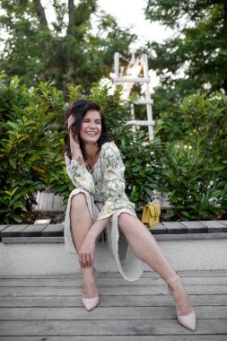 çiçek bahar yaz bluz esmer genç kadın. Kız verandada poz. Yaz çiçek kıyafeti. Şık dalgalı saç modeli. Moda fotoğraf.