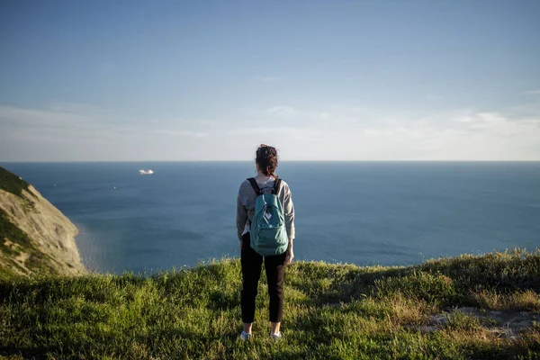 Młoda Kobieta Turysta Plecaka Stojący Klifie Czekamy Tle Morza Niebo — Zdjęcie stockowe