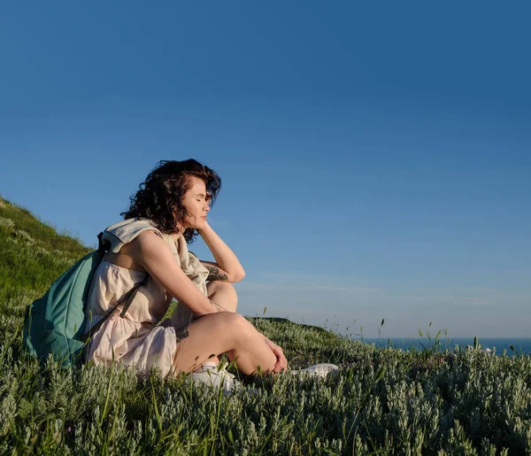 Beautiful Brunette Woman Sitting Grass Hill Sea Travel Woman Backpack — Stock Photo, Image