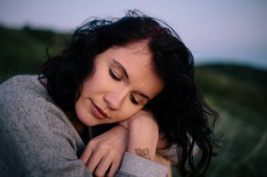 deniz üzerinde çim Hill'de oturan dalgın güzel esmer kadın. Kız açık havada rahatlatıcı.  