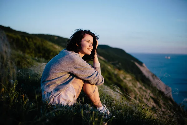 Улыбаясь Красивая Брюнетка Женщина Сидя Траве Холмы Море Девушка Расслабляющий — стоковое фото