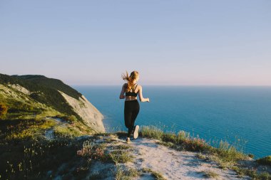 Deniz kenarında köy yolunda çalışan genç çekici spor kadın. Kız genç egzersiz açık tarih. jogging, eğitim, fitness, sağlıklı yaşam, spor ve sağlık kavramı