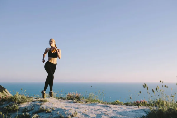 海の近くの田舎道を走っている若い魅力的なスポーツ女性 屋外トレーニングの代で女の子 ジョギング トレーニング フィットネス 健康的なライフ スタイル スポーツ ウェルネスのコンセプト — ストック写真