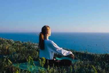Genç kadın pratik Yoga yılında Lotus pozisyonu açık. genç kız deniz yakınlarındaki tepe üzerinde rahatlatıcı. Sakin, meditasyon, koşu, kavramını eğitim, rahatla, sağlıklı yaşam ve sağlık 
