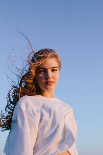 portrait of beautiful young woman outdoor on background of sky on sunrise. Pretty girl teenager on nature. Copy space. Freedom, romantic, fashion, wellness, healthy concept