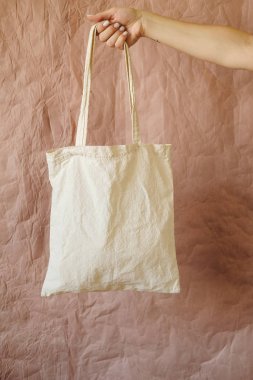 Eko pamuklu kumaş çanta çantası. Tekrar kullanılabilir ürün torbası. Marketten bedava plastik alışveriş poşeti. Sıfır atık daha az plastik yaşam tarzı kavramı kullanın. Kahverengi arkaplanda izole edilmiş boş şablonu düzenle