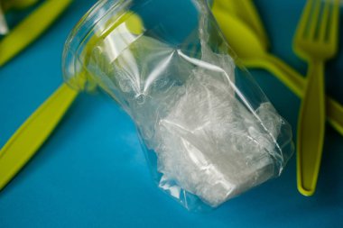 Plastik kaşıklar, çatallar ve bardaklar, tek kullanımlık, tek kullanımlık sofra takımı, plastik kirlilik, atık madde, ekoloji, geri dönüşüm. Plastik işleme sorunu