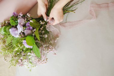 Kadın çiçekçi, kapalı alanda mor çiçeklerden buket yapıyor. Çiçekçide buket hazırlayan kadın çiçekçi. Girişimcilik, küçük işletme, iş yeri konsepti. Boşluğu kopyala