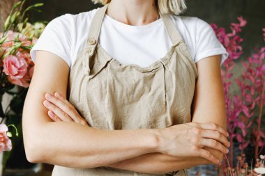 Çiçek arka planında duran önlüklü kadın. Girişimcilik, çiçekçilik, zanaatçılık, zanaat, hizmet, aşçılık, barista, küçük işletme, işyeri konsepti