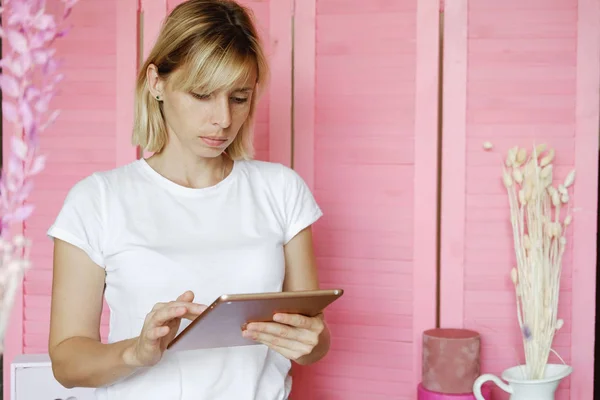 Woman freelancer with tablet indoor. Female florist using tablet to place an order on bouquet  flower shop