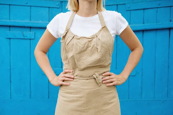 woman in apron standing on wooden vintage background. Entrepreneurship, craftsman, artisan, craft, service, cook, barista, small business, workplace concept. Mock up