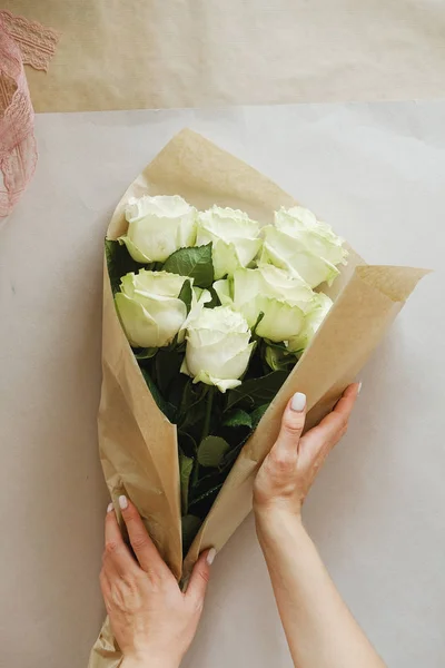 woman florist making bouquet of white flowers indoor. Female florist preparing bouquet of roses at flower shop. entrepreneurship, small business, workplace concept
