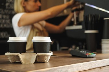 İki fincan kahve ve arka planda kahve makinesi olan bayan barista..