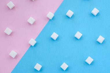 Pembe ve mavi arkaplanda şeker küpleri. Diyabet, şeker hastalığı, sağlıksız yiyecekler, diyet konsepti. Boşluğu kopyala