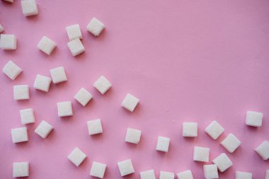 Şeker küpleri ve tatlandırıcı pembe arka planda. Diyabet, şeker hastalığı, sağlıksız yiyecekler, diyet konsepti. Boşluğu kopyala