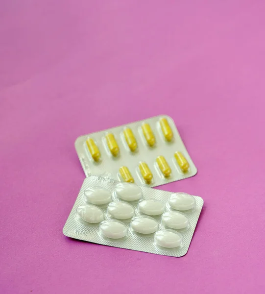 pharmaceutical medicine pills, tablets and capsules on pink background. Copy space