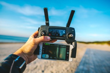 Mavi gökyüzü deniz ve plaj ve el holding denetleyicisi ile smartphone üzerinde uçan robot