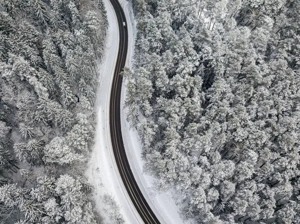 Vista aérea do drone da estrada na floresta nevada — Fotografia de Stock