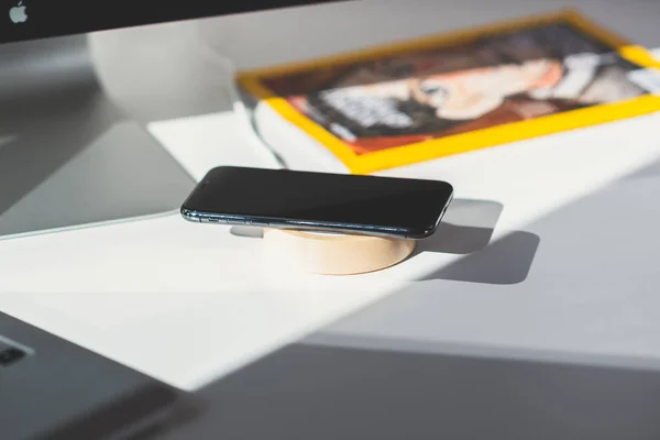 IPhone x Smartphone und drahtloses Ladegerät auf Arbeitstisch — Stockfoto