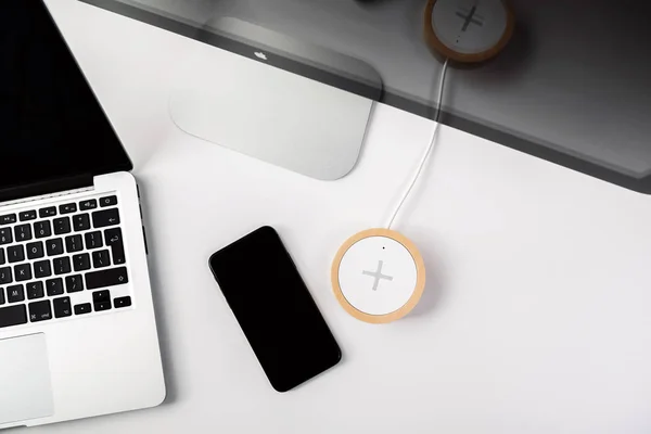 IPhone X smart phone and wireless charger on working table — Stock Photo, Image