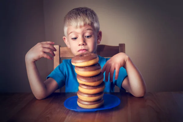 Jonge jongen kijken Donuts — Stockfoto