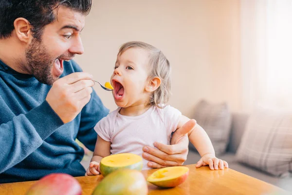 Close Young Father Feeding Cute Little Girl Fresh Mango Home — Stock Photo, Image