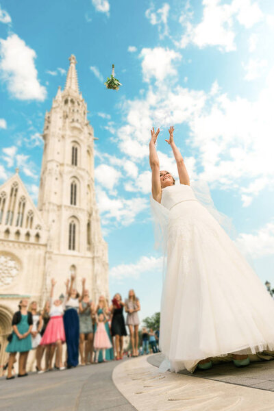 young, beautiful and elegant bride wearing white wedding dress and throwing bouquet