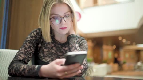 Blonde Junge Frau Mit Brille Benutzt Smartphone Einkaufszentrum — Stockvideo