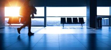 İnsanlar gün batımında havaalanında yürüyorlar. Tanımlanamayan bulanık siluet